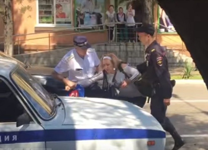 Беременной женщине полицейский заламывает руки Скриншот видео из социальных сетей